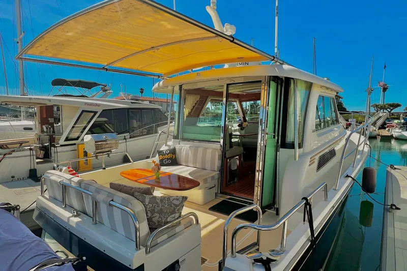 Slide: The Image of 2016 Sabre 38 Salon Express yacht docked, featuring a spacious outdoor seating area under a canopy. - 2