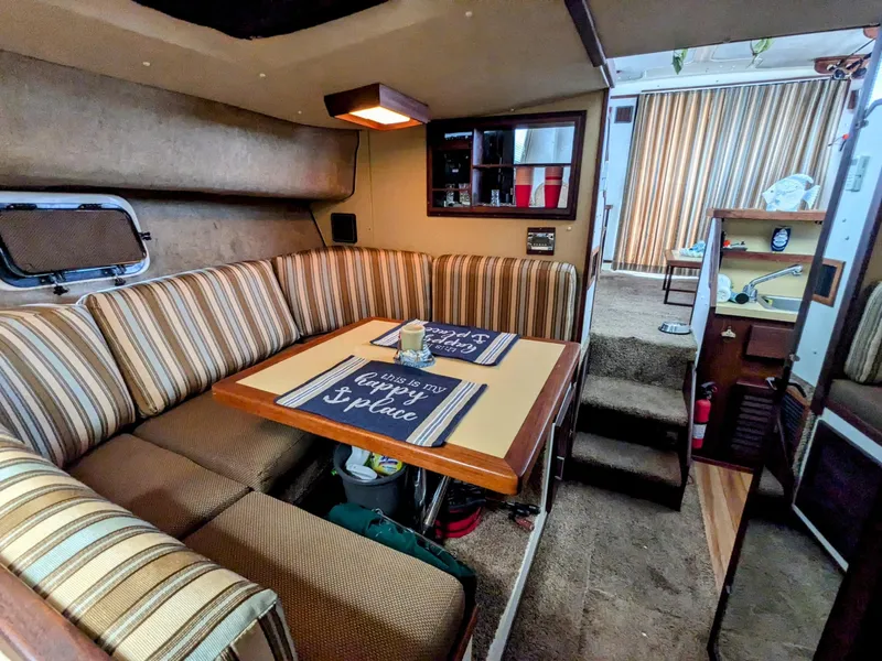Slide: The Image of 1981 Silverton 37 Convertible interior with striped seating, dining table, and cozy decor. - 16