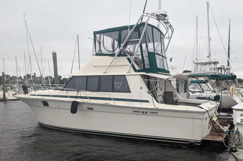 Slide: The Image of 1981 Silverton 37 Convertible boat docked at marina, featuring green canopy and classic design. - 2