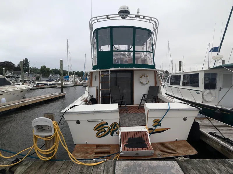 Slide: The Image of 1981 Silverton 37 Convertible docked at marina, rear view with green canopy. - 3
