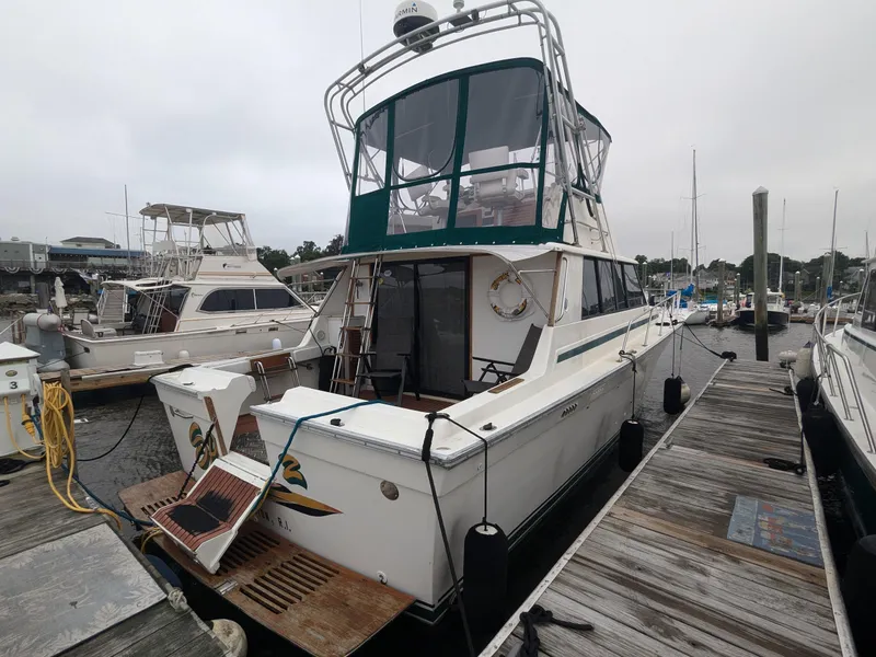 Slide: The Image of 1981 Silverton 37 Convertible docked at a marina, featuring a green canopy and wooden deck. - 4