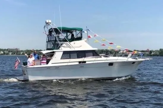 Slide: The Image of 1981 Silverton 37 Convertible boat cruising on a lake with colorful flags and passengers. - 5