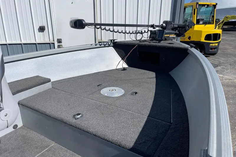 Slide: The Image of 2016 Alumacraft Escape 145 Tiller boat interior with trolling motor, docked near a warehouse. - 5