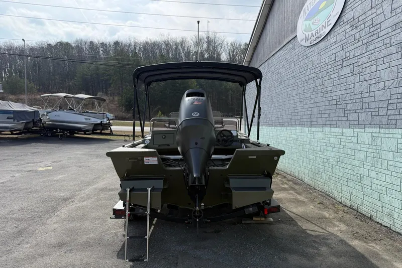 Slide: The Image of 2026 SeaArk Easy 200 boat with outboard motor, parked outdoors near a marine shop. - 6