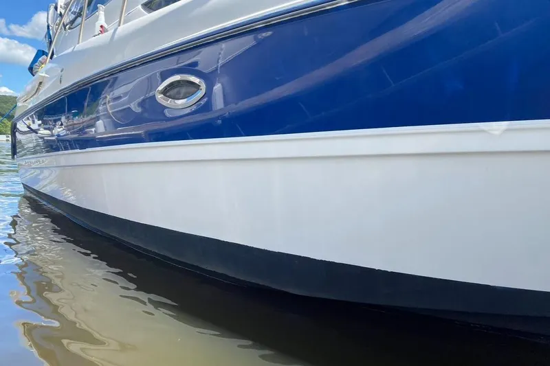 Slide: The Image of 2005 Bayliner 305 boat with blue and white hull on calm water. - 17