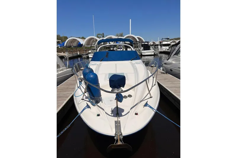 Slide: The Image of 2005 Bayliner 305 boat docked at marina, featuring blue covers and fenders. - 18