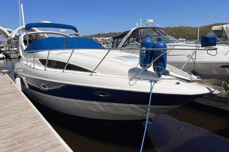 Slide: The Image of 2005 Bayliner 305 boat docked at marina, featuring blue and white design. - 19