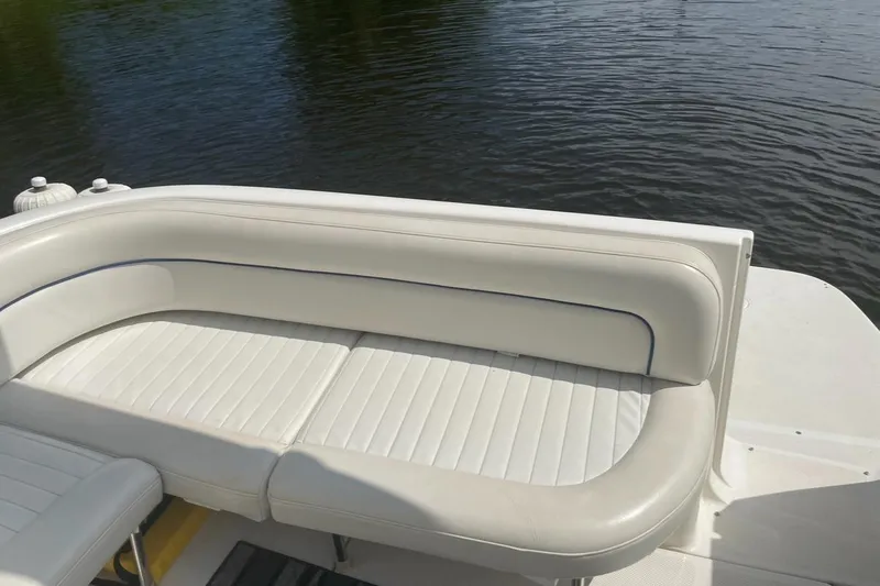 Slide: The Image of 2005 Bayliner 305 boat with white cushioned seating by the water. - 21