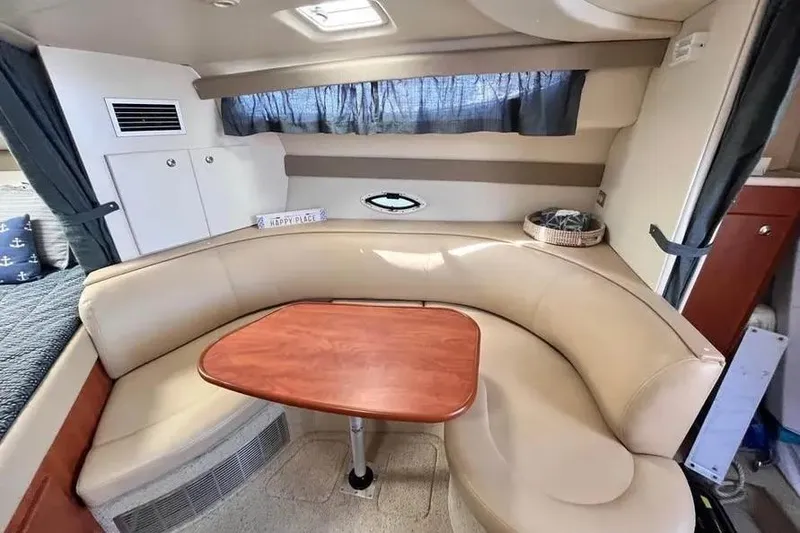 Slide: The Image of 2005 Bayliner 305 interior with beige seating and wooden table in cozy cabin. - 4