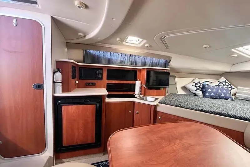 Slide: The Image of 2005 Bayliner 305 cabin interior with kitchenette, bed, and wooden cabinetry. - 5