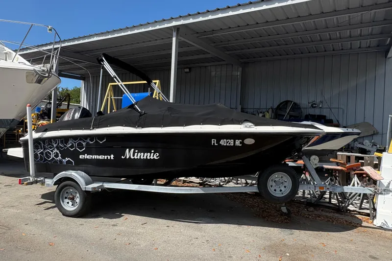 The Image of 2016 Bayliner 160 Bowrider boat named "Minnie" on a trailer under a metal shelter. - 1