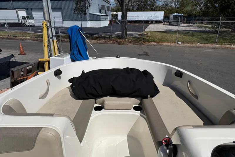 Slide: The Image of 2016 Bayliner 160 Bowrider boat interior with seating and storage, parked outdoors. - 6