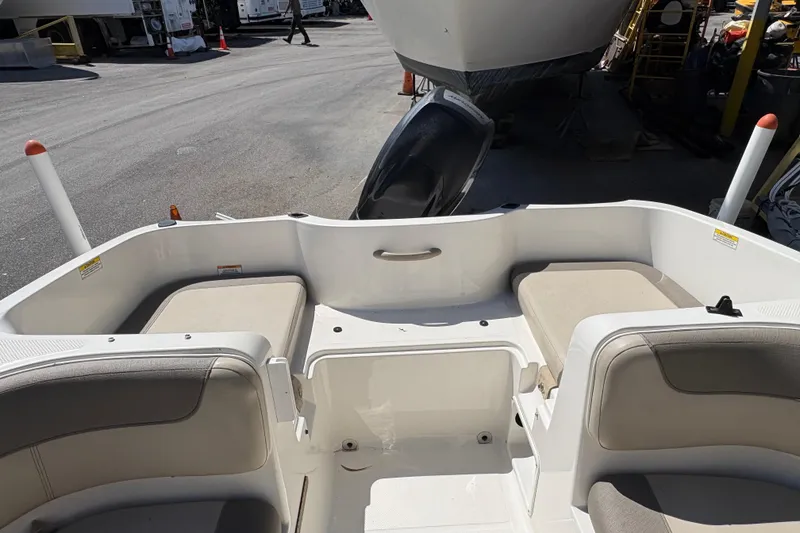 Slide: The Image of 2016 Bayliner 160 Bowrider interior with cushioned seating, parked in a marina. - 8