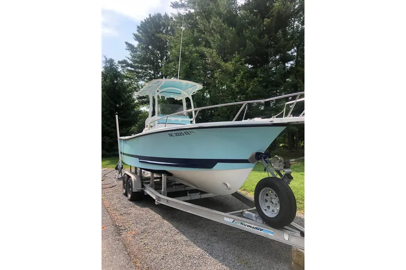 The Image of 2001 Shamrock 22 Open Center Console boat on trailer, surrounded by trees. - 1