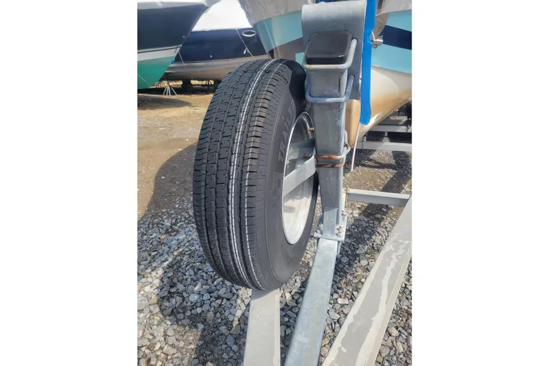 Slide: The Image of Trailer wheel of a 2001 Shamrock 220 Open boat on gravel surface. - 33
