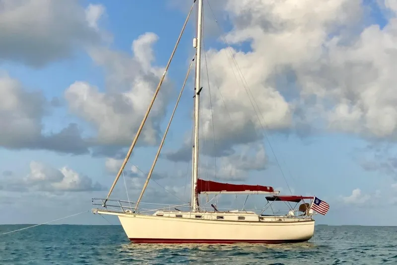 The Image of 1988 Island Packet 38 sailboat anchored on calm sea under cloudy sky. - 0