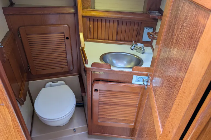 Slide: The Image of 1988 Island Packet 38 yacht bathroom with wooden cabinetry, sink, and toilet. - 18