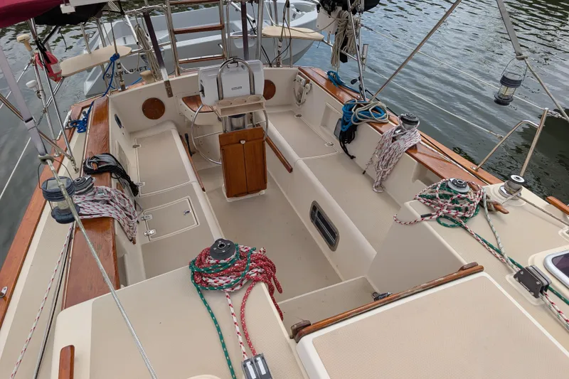 Slide: The Image of 1988 Island Packet 38 sailboat cockpit with ropes and wooden accents on calm water. - 25