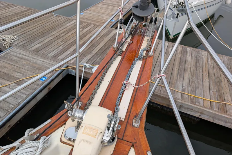 Slide: The Image of Bow of 1988 Island Packet 38 sailboat docked, featuring anchor chain and wooden deck. - 36