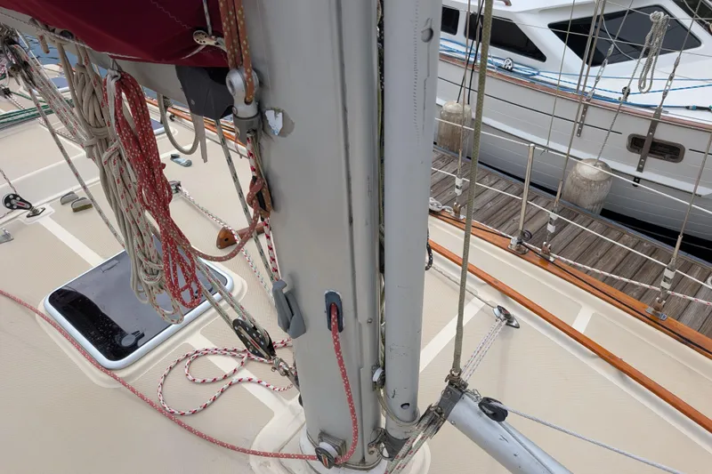 Slide: The Image of 1988 Island Packet 38 sailboat deck with mast, ropes, and docked yacht in background. - 40