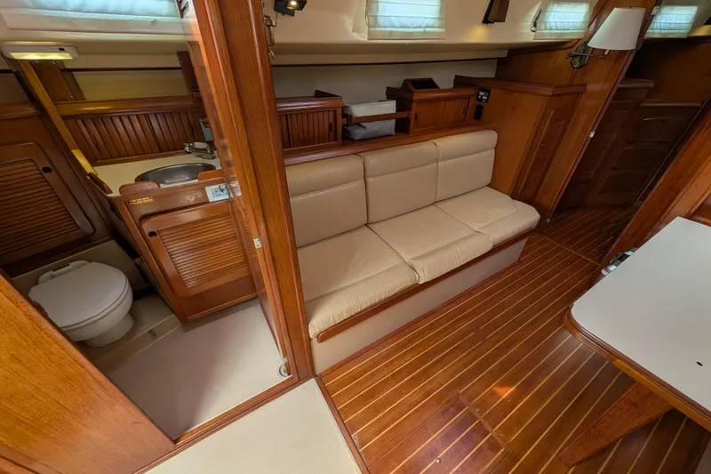 Slide: The Image of 1988 Island Packet 38 yacht interior with wooden finish, featuring a cozy seating area and compact bathroom. - 5
