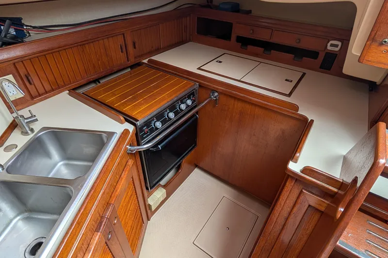 Slide: The Image of 1988 Island Packet 38 yacht kitchen with wooden cabinetry, stove, and double sink. - 8