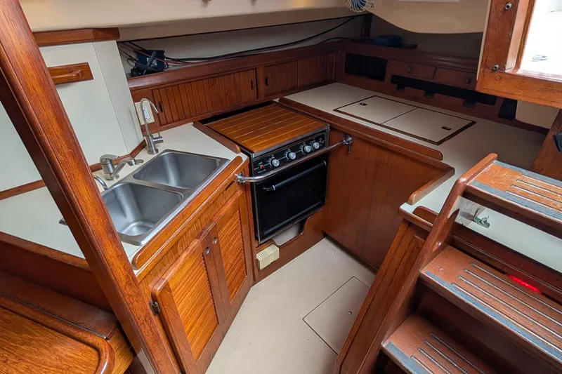 Slide: The Image of 1988 Island Packet 38 yacht kitchen with wooden cabinetry, dual sink, and stove. - 9