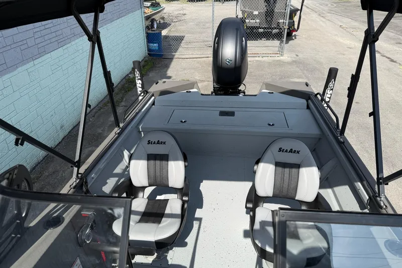 Slide: The Image of 2026 SeaArk Protege 200 boat interior with dual seats and motor, parked outdoors. - 8