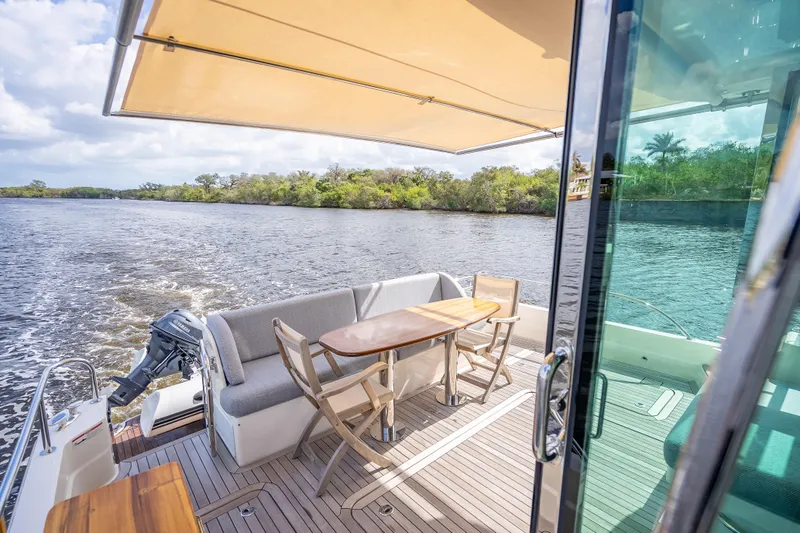 Slide: The Image of 2025 Sabre 58 Salon Express yacht deck with seating, table, and scenic water view. - 15