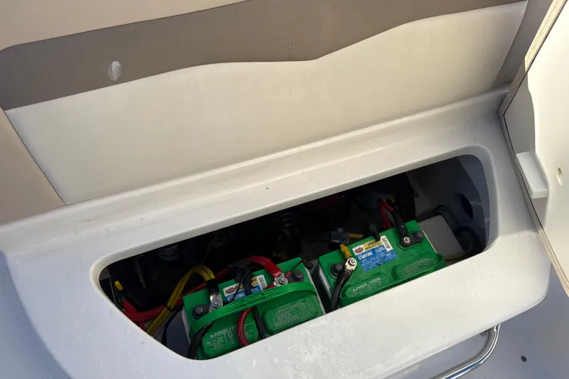 Slide: The Image of 2012 Chaparral 246 SSi boat battery compartment with visible green batteries. - 13