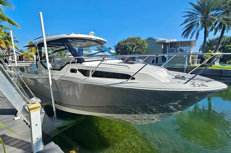 Slide: The Image of 2025 Boston Whaler 325 Conquest boat docked in sunny waterfront setting. - 0