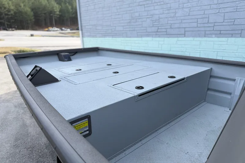 Slide: The Image of 2026 SeaArk 2472 CUB boat interior with storage compartments, parked outdoors. - 7