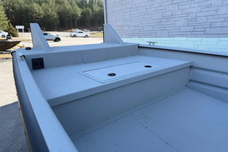 Slide: The Image of 2026 SeaArk 2472 Workhorse boat interior with storage compartment, parked outdoors. - 5