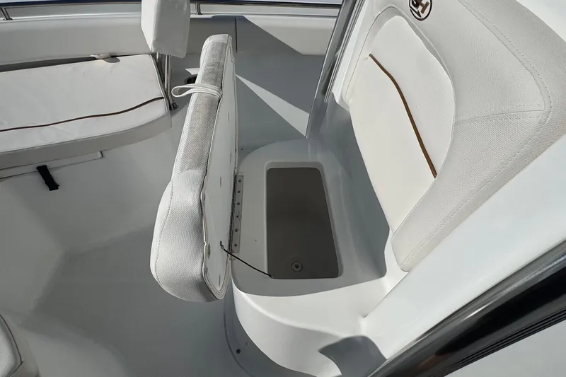 Slide: The Image of 2023 Sea Hunt Ultra 234 boat interior with white cushioned seating and storage compartment. - 12