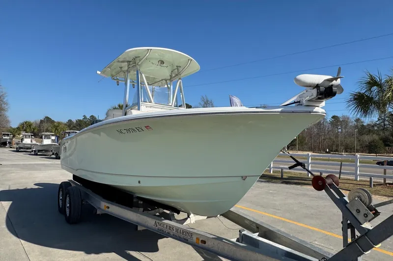Slide: The Image of 2023 Sea Hunt Ultra 234 boat on trailer, parked outdoors under clear blue sky. - 6