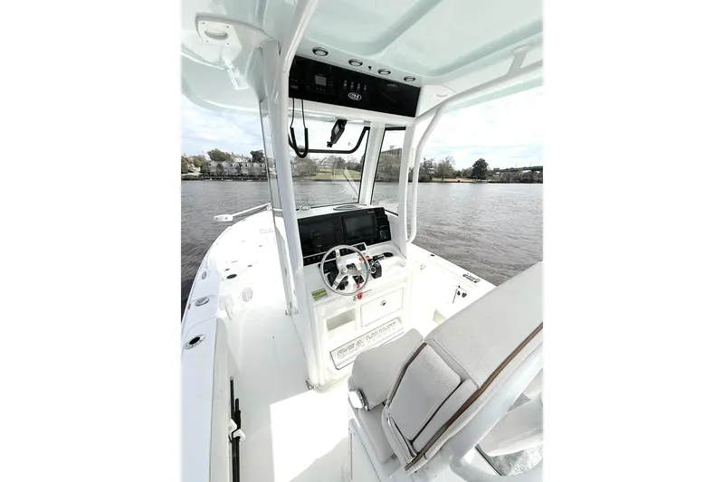Slide: The Image of 2020 Sea Hunt BX 25 FS boat interior with steering console on a calm waterway. - 16