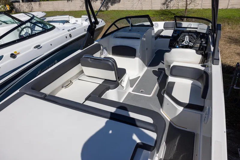 Slide: The Image of 2021 Bayliner VR6 Bowrider OB interior with seating and steering wheel, docked beside another boat. - 4