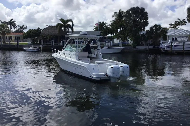 Slide: The Image of 2017 Robalo R305 Walkaround boat cruising on a calm waterway with palm trees. - 2