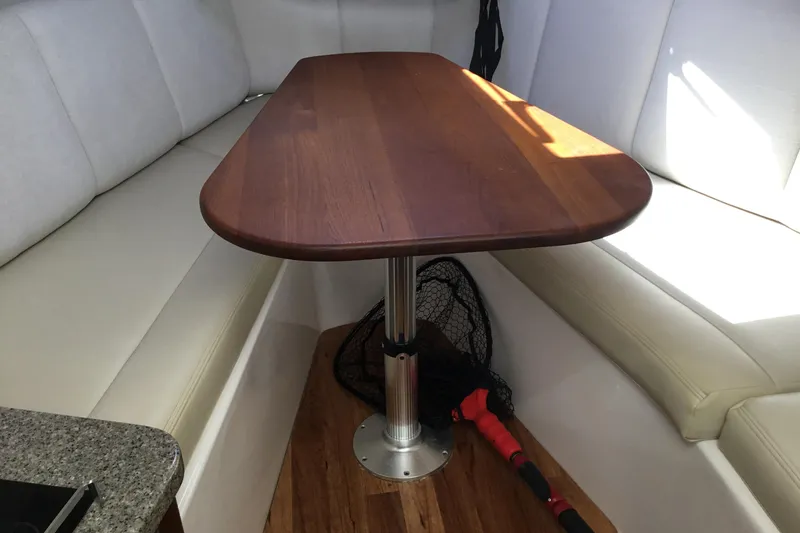 Slide: The Image of 2017 Robalo R305 Walkaround cabin interior with wooden table and cushioned seating. - 35