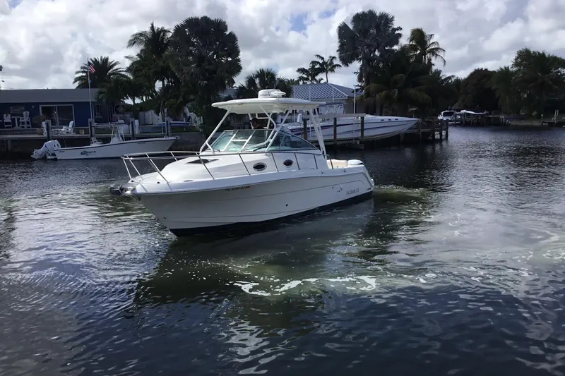 Slide: The Image of 2017 Robalo R305 Walkaround boat cruising on a calm waterway with palm trees. - 4