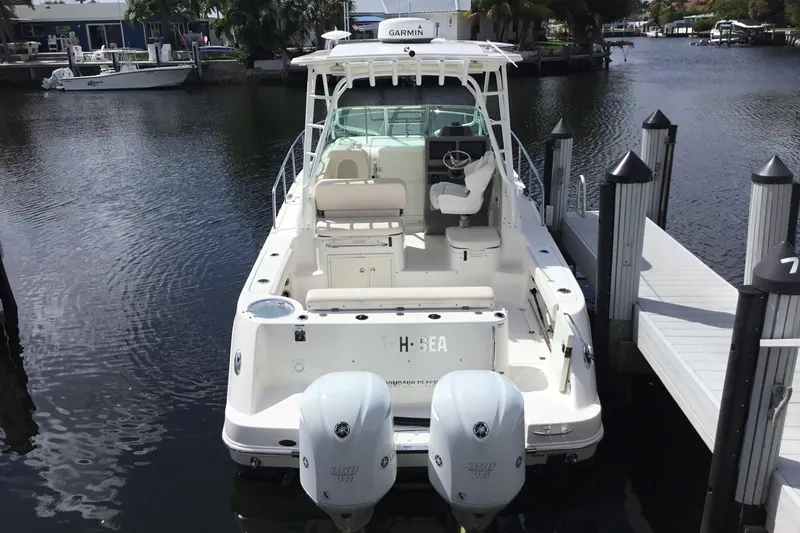 Slide: The Image of 2017 Robalo R305 Walkaround boat docked, featuring dual engines and spacious deck. - 5