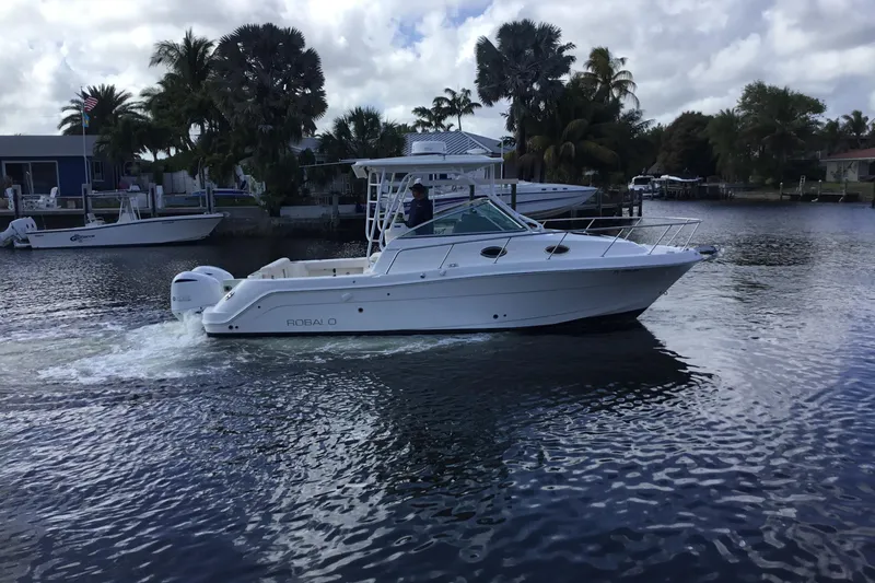 Slide: The Image of 2017 Robalo R305 Walkaround boat cruising on a calm waterway with palm trees. - 50
