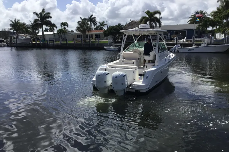 Slide: The Image of 2017 Robalo R305 Walkaround boat cruising on a calm waterway with palm trees in the background. - 6