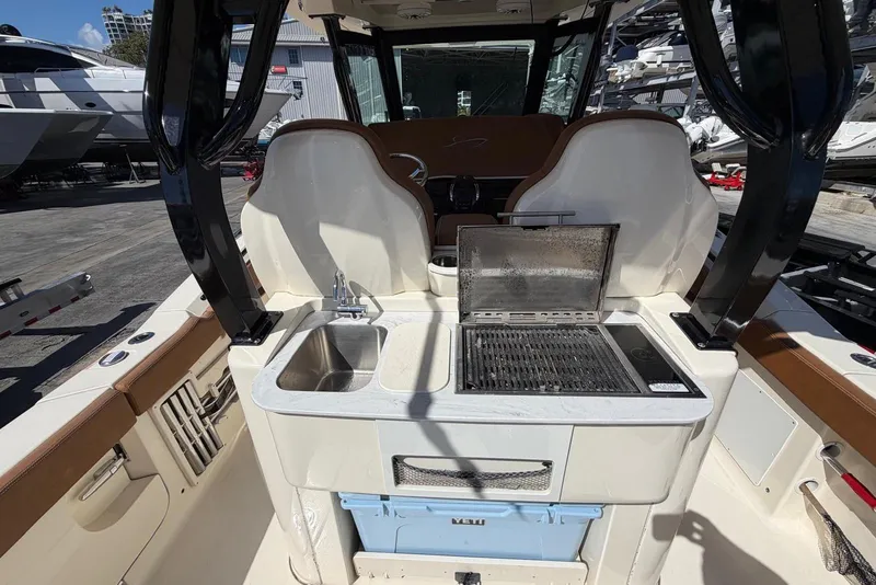 Slide: The Image of 2021 Scout 330 LXF boat with onboard sink and grill in marina setting. - 12
