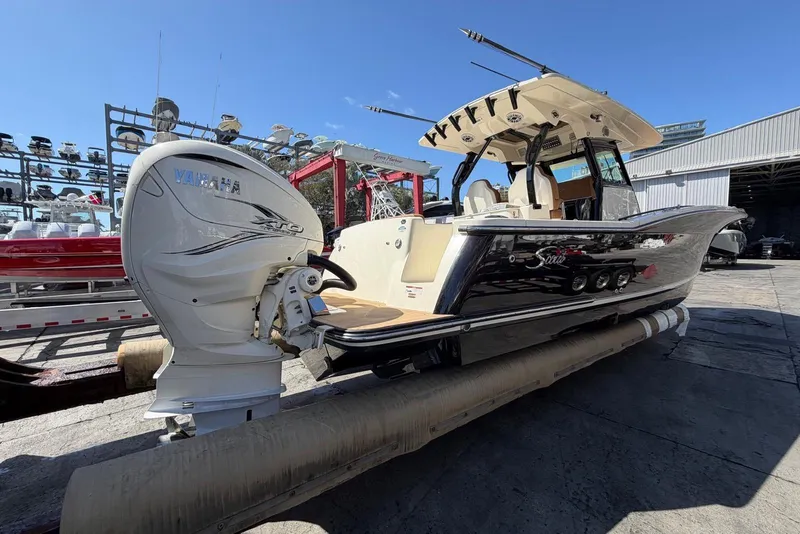 Slide: The Image of 2021 Scout 330 LXF boat with Yamaha engine, docked outdoors under clear blue sky. - 2