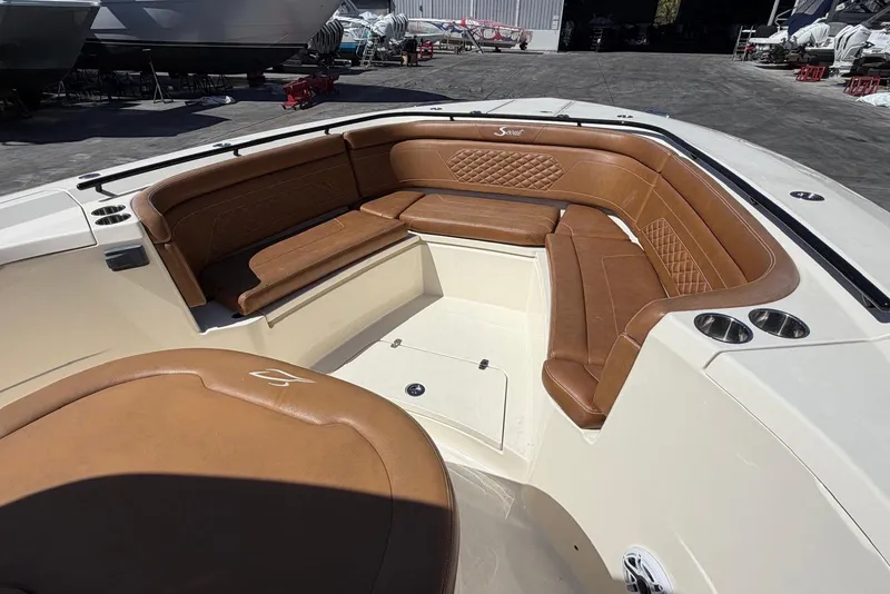 Slide: The Image of 2021 Scout 330 LXF boat with luxurious brown leather seating in a marina setting. - 9