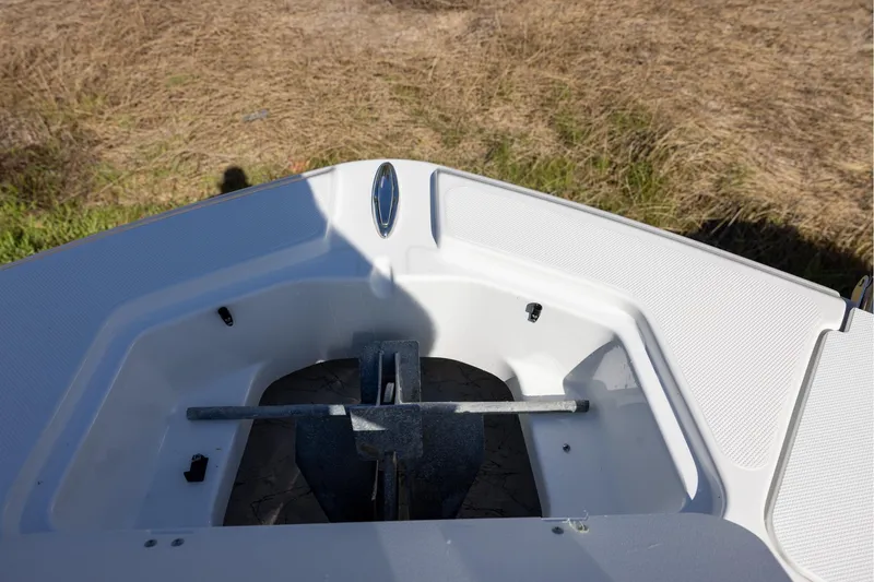 Slide: The Image of 2023 Hurricane SunDeck 2400 OB boat anchor compartment, open and empty, on grassy background. - 14
