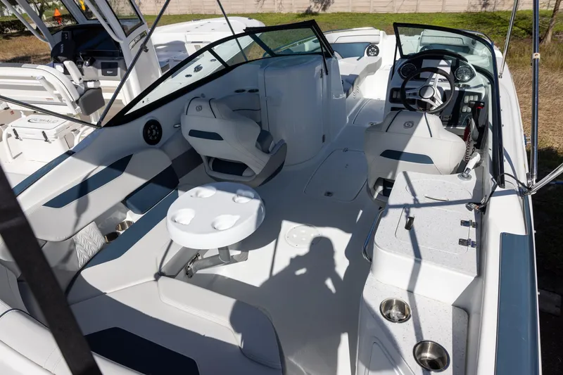 Slide: The Image of 2023 Hurricane SunDeck 2400 OB boat interior with seating, steering wheel, and table. - 5