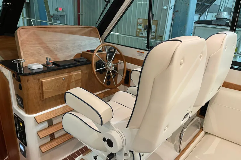 Slide: The Image of 2026 Back Cove 372 helm with wooden dashboard and plush white seating. - 10