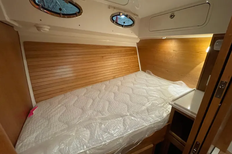Slide: The Image of 2026 Back Cove 372 cabin interior with wooden paneling and a neatly made bed. - 17